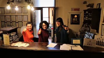 Una reception con documenti, un lampadario, certificati incorniciati e un cartello che promuove un marchio di vino.