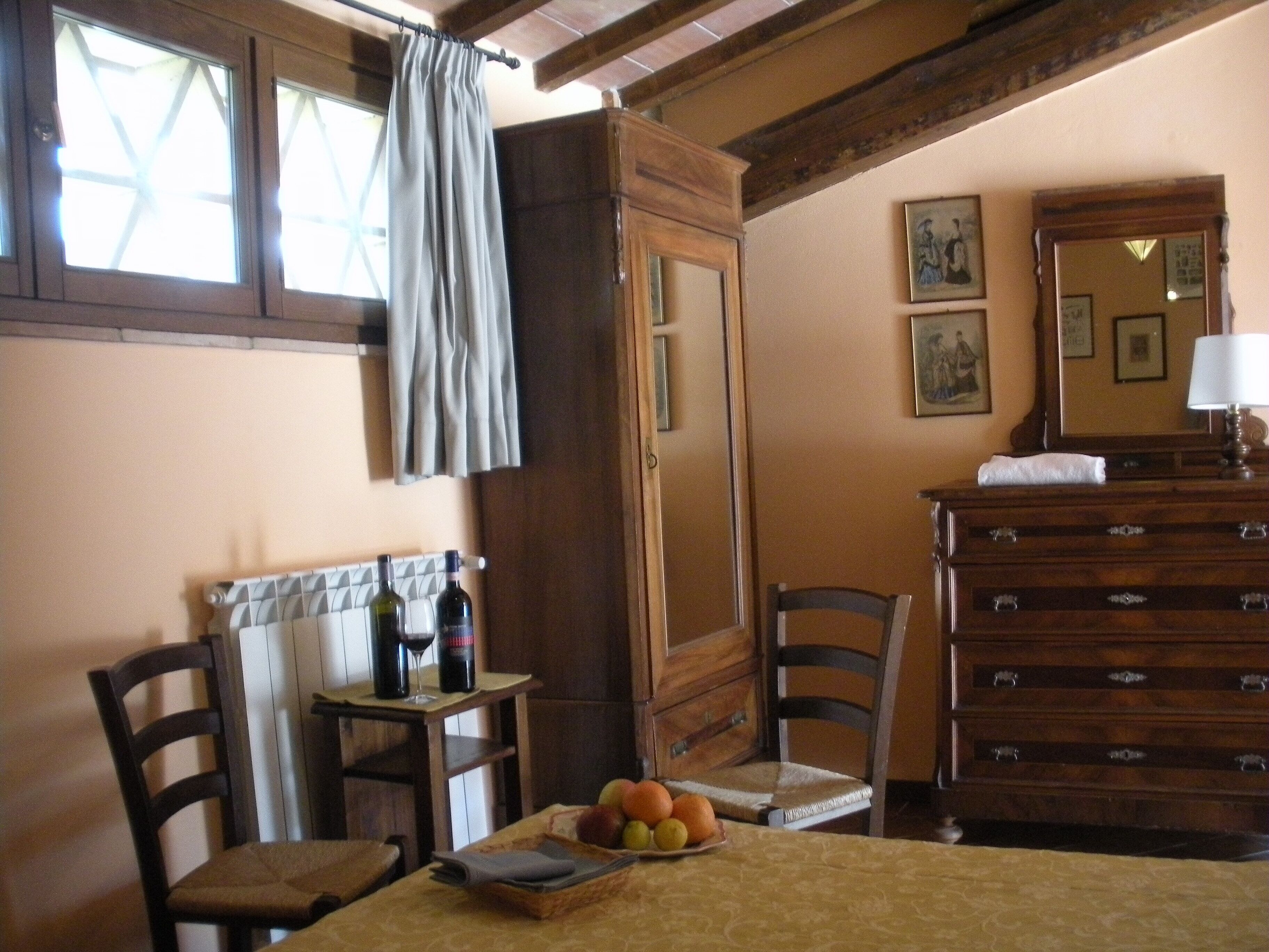 A dining area with a table set for two, a wooden cabinet, and a mirror.