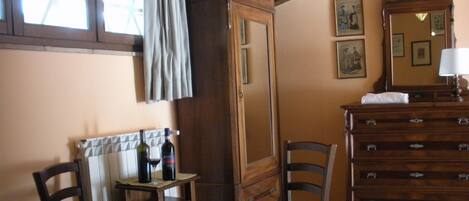 A dining area with a table set for two, a wooden cabinet, and a mirror.