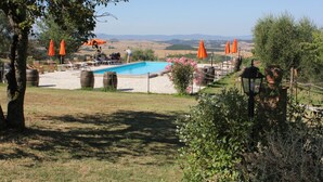 A pool area with orange umbrellas, a clear view of the countryside, and a rustic setting. - Agriturismo Fattoria Del Colle (Trequanda)