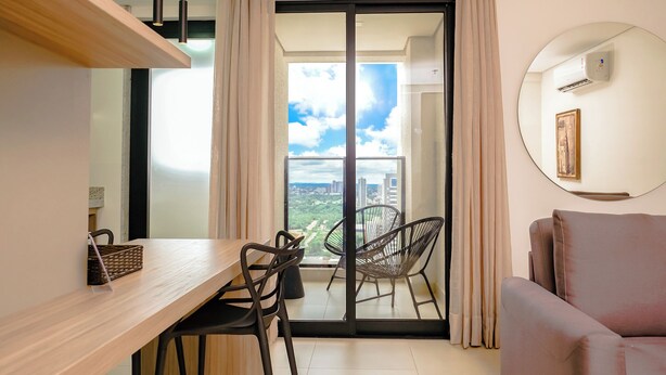 A balcony with a view of the city, a round mirror, a sofa, and a dining area with chairs and a table.