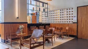 Een modern interieur met houten lambrisering, een receptiebalie en een zithoek met stoelen en tafels.