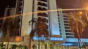 A modern hotel building with multiple floors, large windows, and a sign indicating it is a hotel.