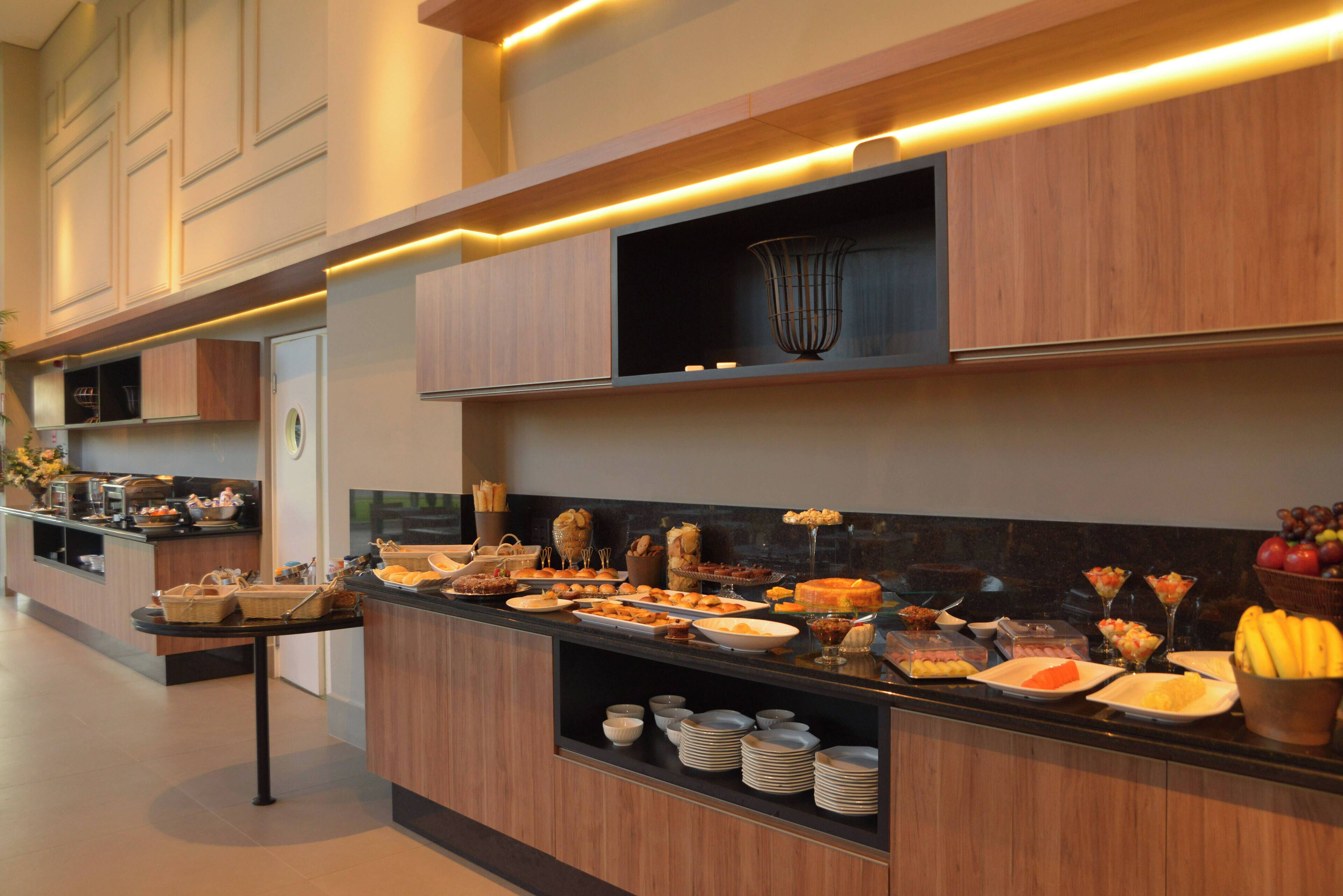 A modern kitchen with a buffet setup, featuring various food items and a coffee station.