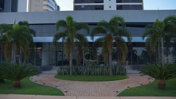 Un edificio moderno con un sendero adoquinado, palmeras y un jardín bien cuidado.