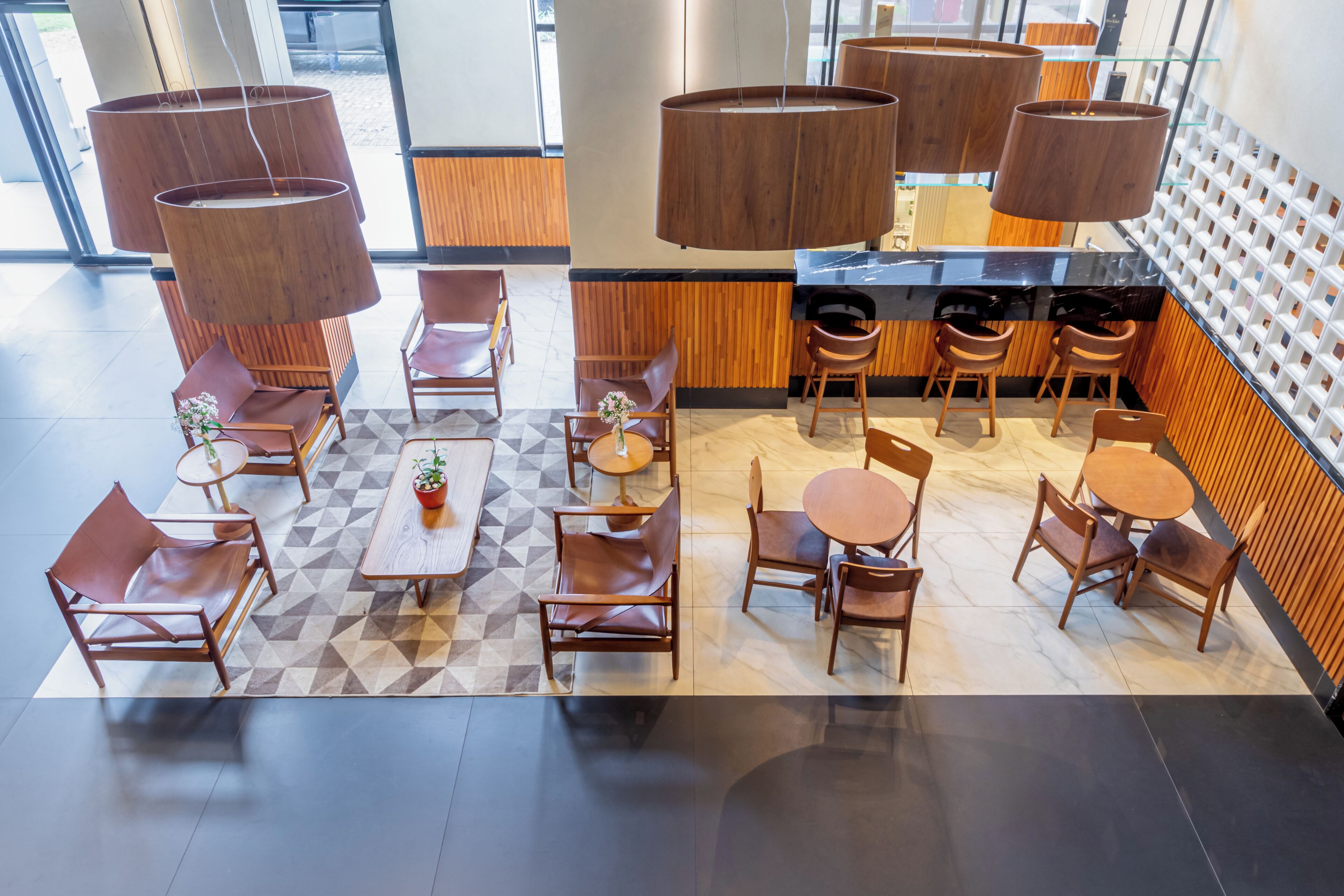 Een modern café met houten meubels, ronde tafels en hangende houten lampen.