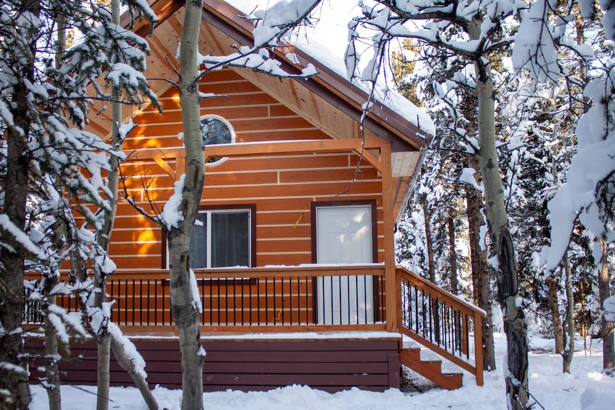 A wooden cabin with a balcony, surrounded by snow-covered trees.