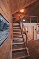 Una escalera de madera que sube a un nivel superior con vistas al exterior.