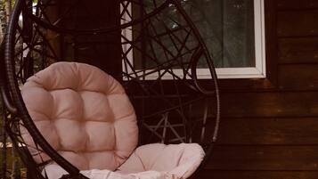 A wicker chair with a cushioned seat and back, positioned on a wooden deck.