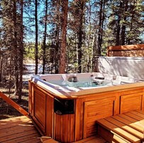 A hot tub in a forested area with wooden deck and benches.