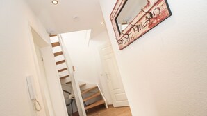Un escalier avec des marches en bois menant à un palier, une porte blanche et un miroir mural encadré d’un cadre rustique.