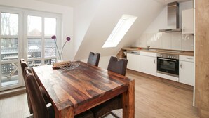 Une cuisine moderne avec une table à manger en bois, des armoires blanches et une lucarne.