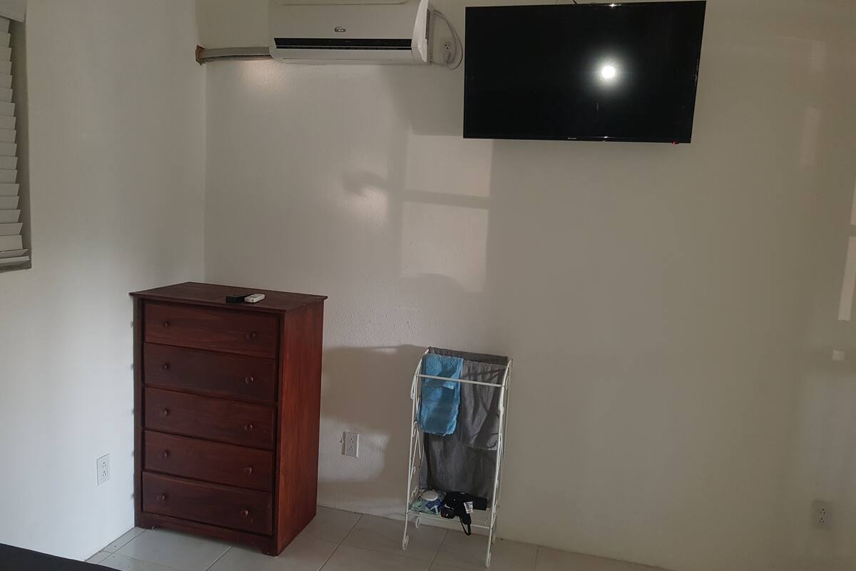 Ein Zimmer mit einem Holzkasten, einer Wandklimaanlage und einem Fernseher.