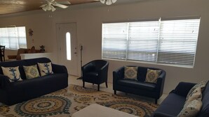 A living room with two dark blue sofas, a black armchair, and a patterned rug. - Nature's Delight Lodge (Colonel Hill)