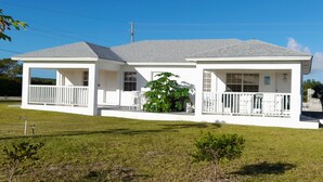 A two-story white house with a covered porch and a small front yard. - Nature's Delight Lodge (Colonel Hill)