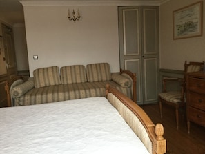 A bedroom with a large bed, a sofa, a wooden dresser, and a door with glass panels. - Mado (Le Crotoy)