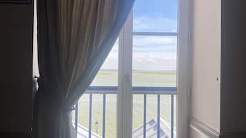 Une fenêtre donnant sur un balcon et un immeuble situé de l’autre côté de l’eau.
