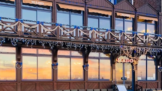 Un immeuble doté de nombreuses fenêtres, d’un balcon avec des chaises et d’une enseigne sur laquelle on peut lire « VIA DADO ».