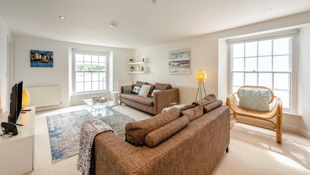 A living room with a sofa, a chair, a coffee table, and a TV. - 2 Bed in Appledore (oc-loblof) (Appledore)