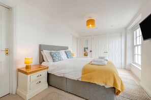 Ein Schlafzimmer mit Bett, Nachttischlampen, einem Nachttisch, einem Kleiderschrank und einem Fernseher.