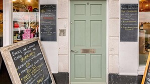 Une porte verte ornée de panneaux noirs sur lesquels sont affichées des promotions et une offre de carte de fidélité.