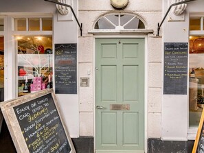 Une porte verte ornée de panneaux noirs sur lesquels sont affichées des promotions et une offre de carte de fidélité.