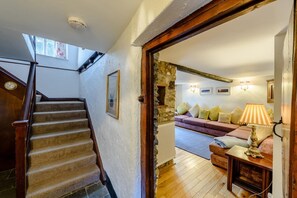 A staircase leading to a living area with a stone wall, a sofa set, and a lamp. - 4 Bed in Croyde (oc-bfarmh) (Croyde)