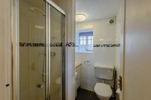 Une salle de bain avec une douche à parois de verre, des toilettes et une fenêtre.