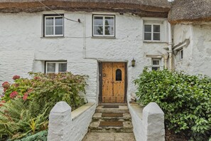 A traditional white building with a wooden door, multiple windows, and a thatched roof.