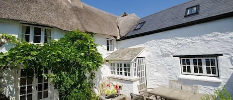 Un bâtiment blanc avec un toit de chaume, une fenêtre et une porte.