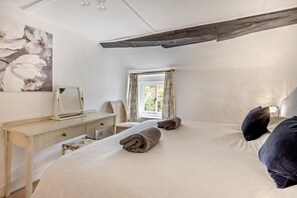 A bedroom with a bed, a desk, a chair, and a window with curtains.
