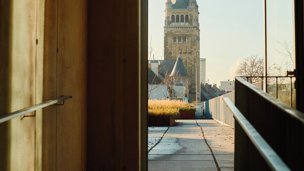 An interior corridor with a view of a historic tower through an open doorway. - THE CLOUTH (Cologne)
