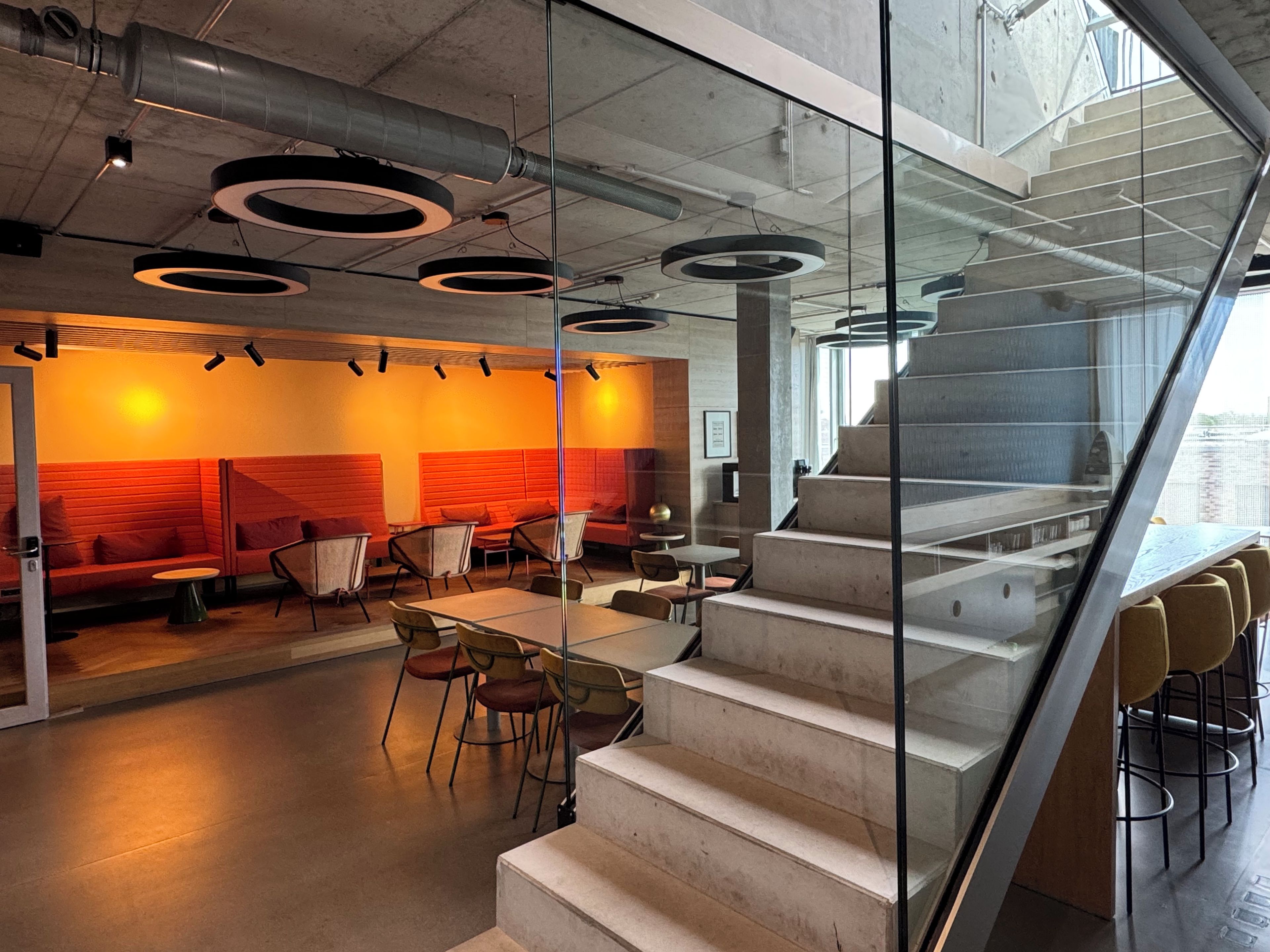 A modern interior with a staircase, seating area, and tables.