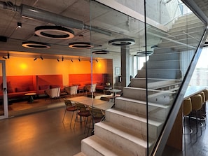 A modern interior with a staircase, seating area, and tables. - THE CLOUTH (Cologne)