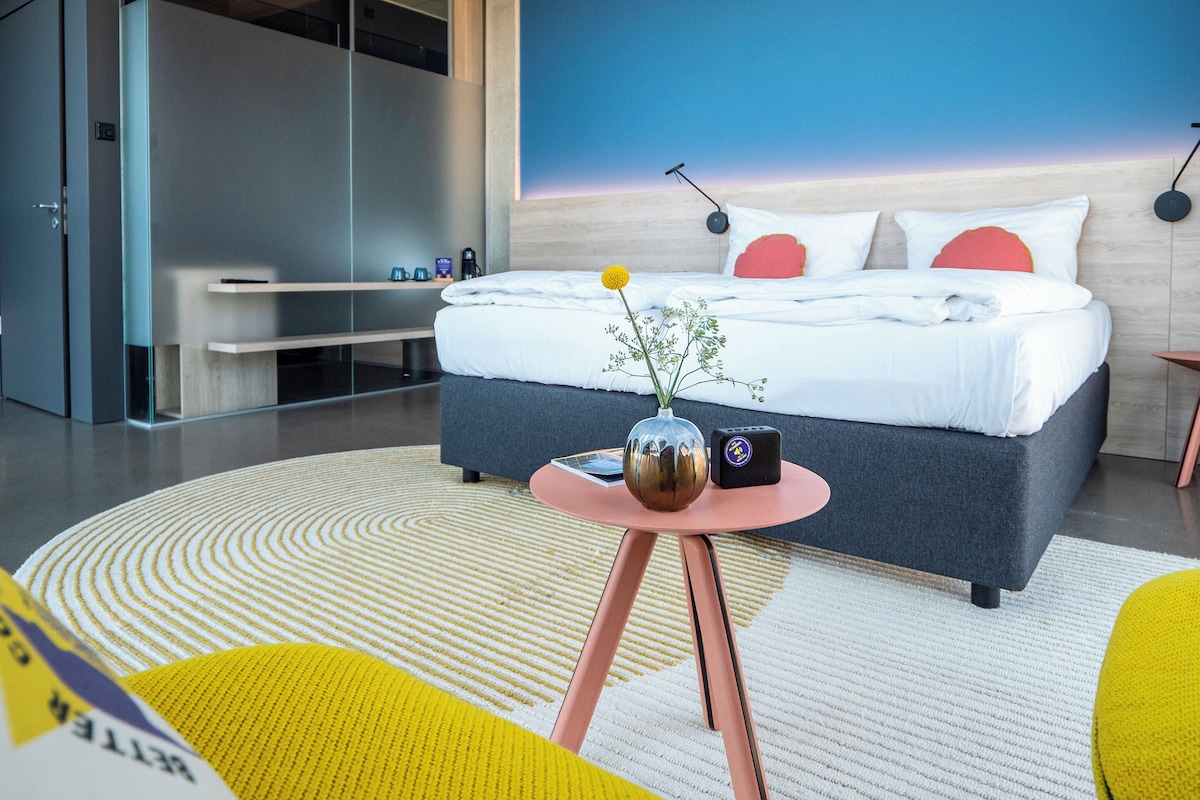 Un dormitorio moderno con cama, mesita de noche y un mural en la pared.