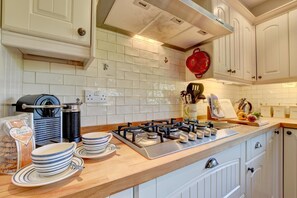 A kitchen with a gas stove, white cabinets, and a tiled backsplash.