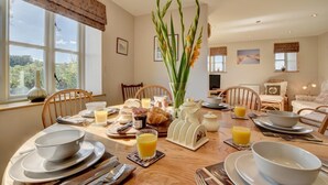 A dining area with a table set for breakfast, including plates, glasses, and a vase with flowers.