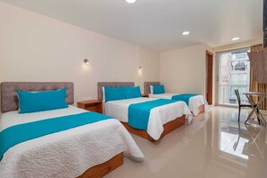 A hotel room with three beds, each with a white and blue bedspread, a wooden headboard, and a small bedside table. - Hostal plaza by Elvita (Baños de Agua Santa)