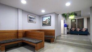 Un área de recepción con bancos de madera y un sofá azul.