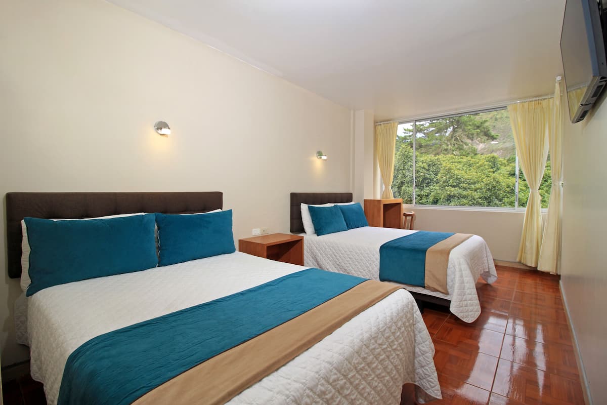 A hotel room with two beds, each with a headboard, a nightstand, and a window with curtains.