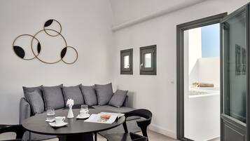 Un salón moderno con una mesa redonda, un sofá gris y un ventanal de vidrio que da a un espacio exterior.