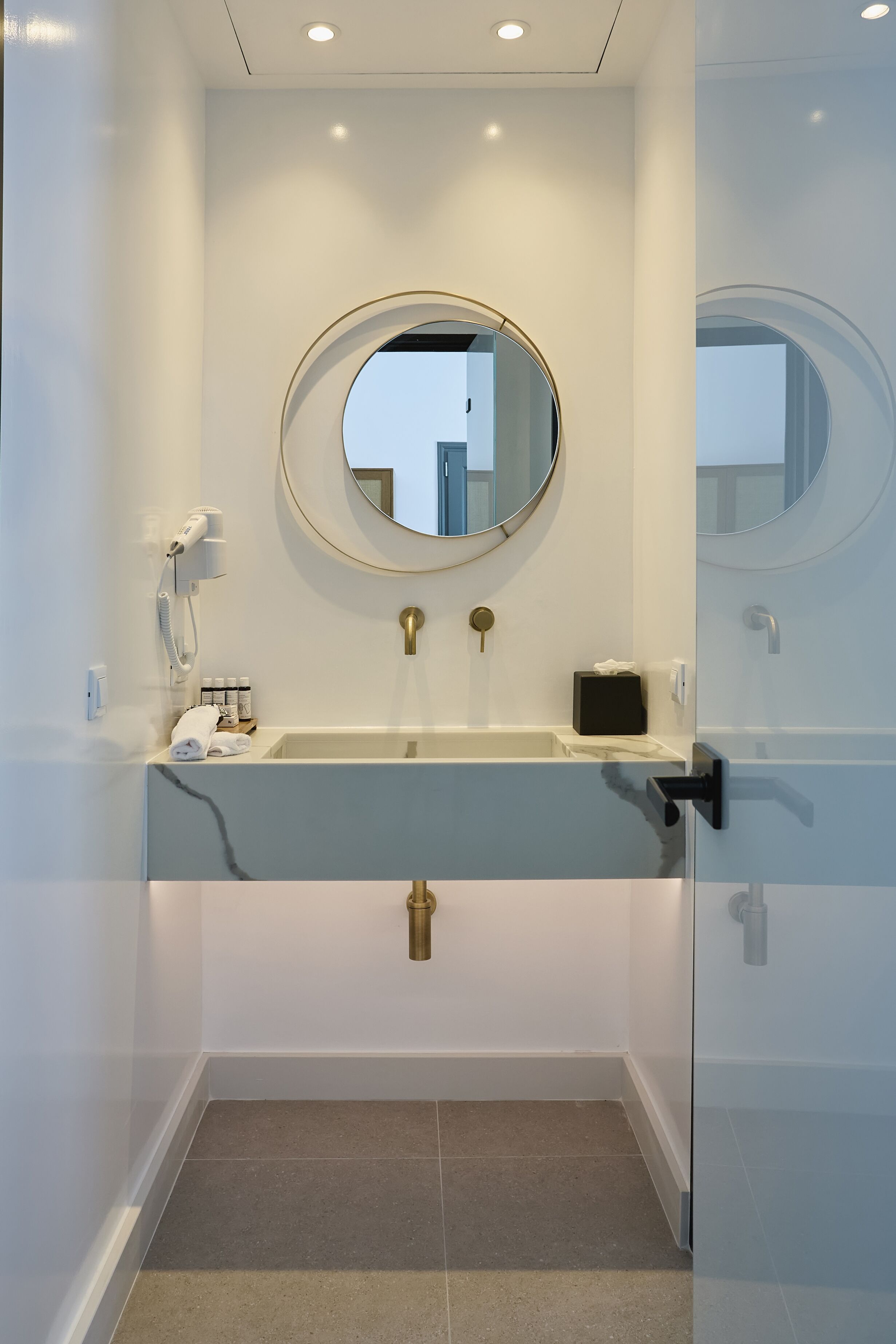 A modern bathroom with a round mirror, a built-in sink, and a towel rack.