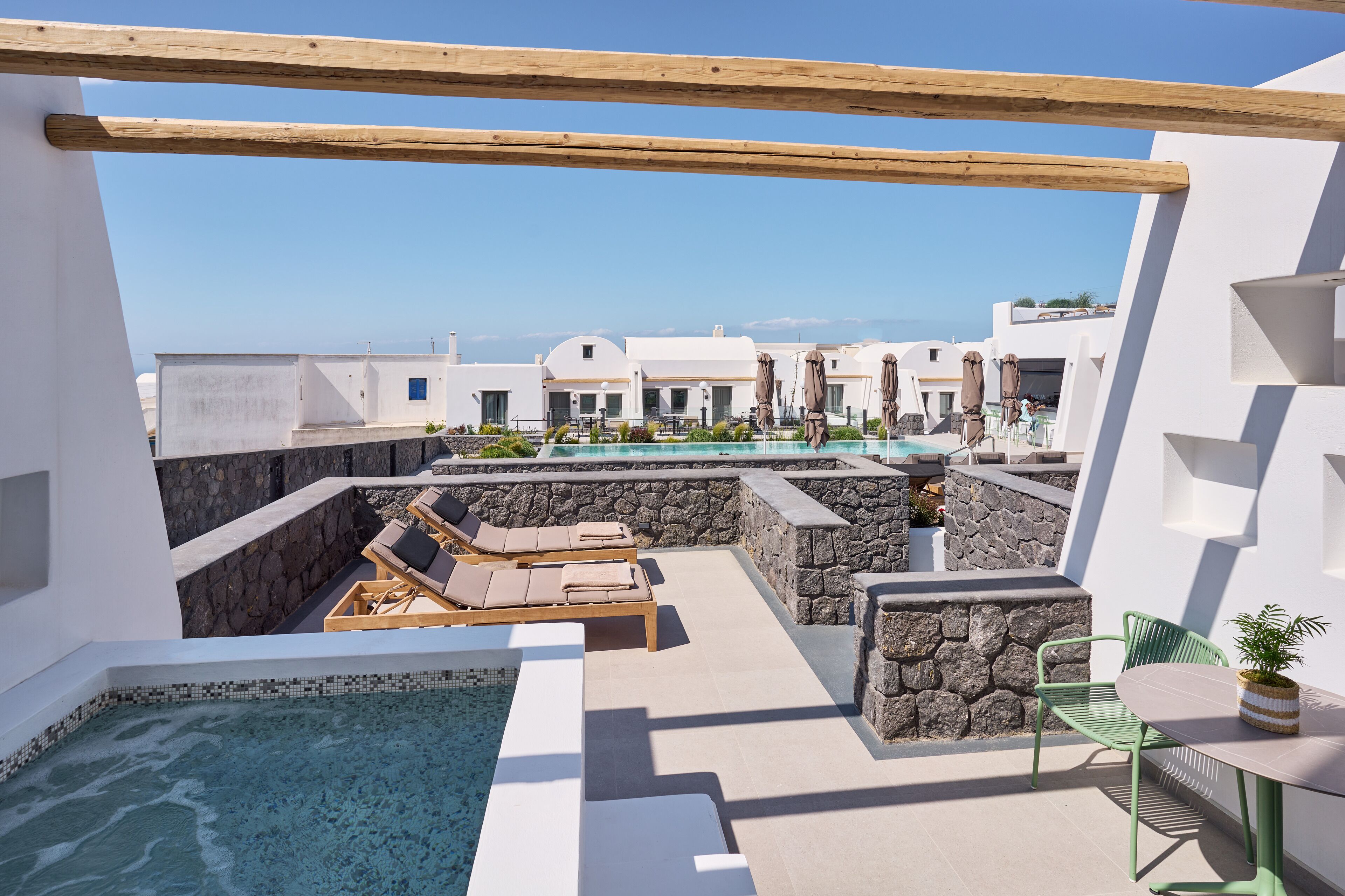 A rooftop pool area with lounge chairs, a table, and a small garden.