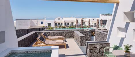 A rooftop pool area with lounge chairs, a table, and a small garden.