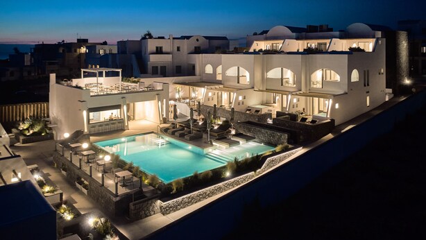 Et moderne hotel med swimmingpool, udendørs siddepladser og bar.