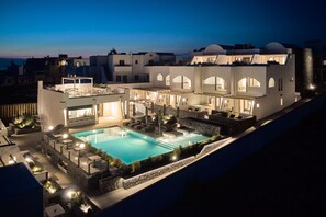 A modern hotel with a swimming pool, outdoor seating, and a bar area.
