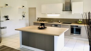 A modern kitchen with a central island, built-in appliances, and minimalist design. - La Gaude, villa 6 people-garden-pool-open view in a quiet (La Gaude)