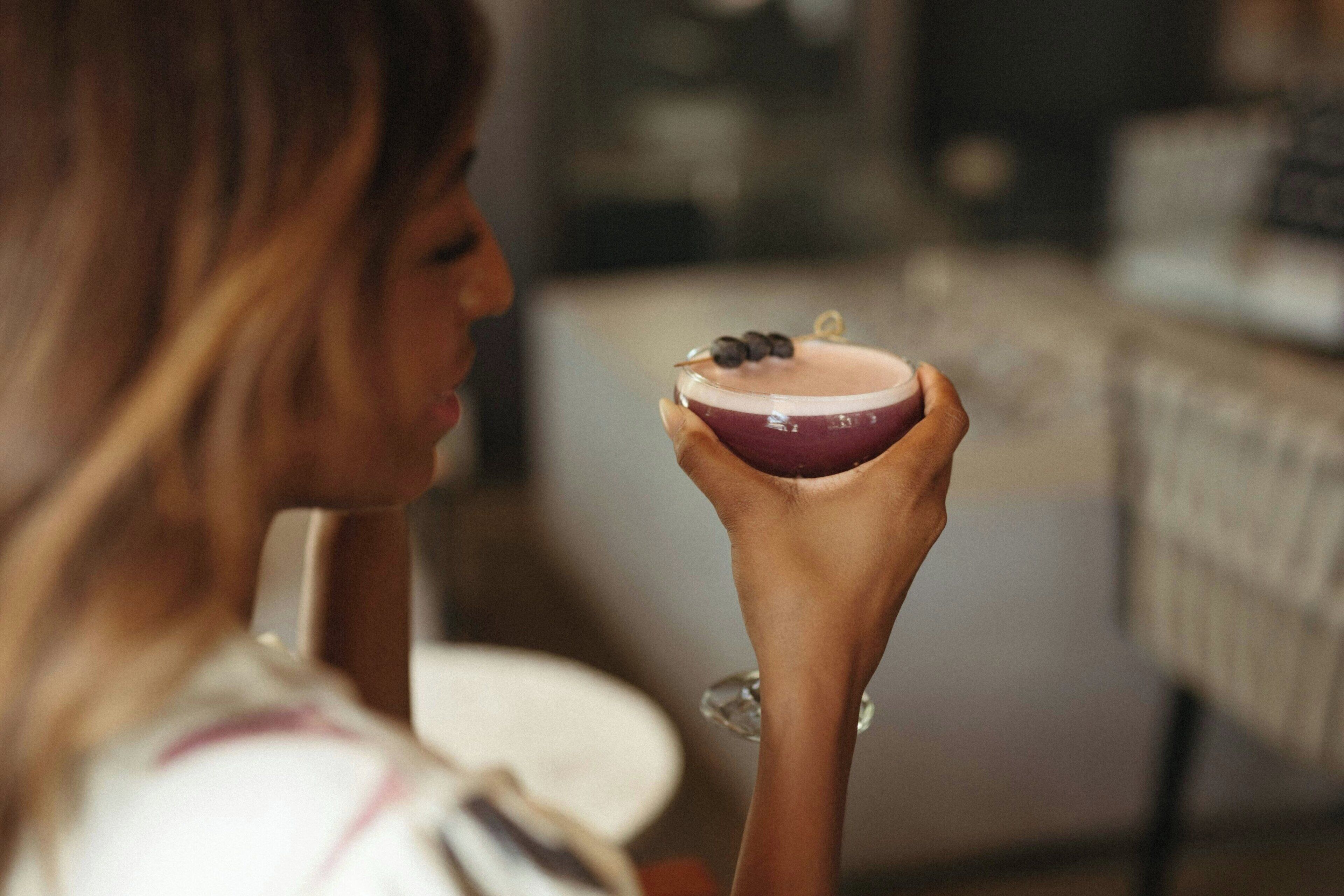 Iemand houdt een klein, rond voorwerp vast met een donkere kern en een lichtere buitenrand, mogelijk een dessert of snack.