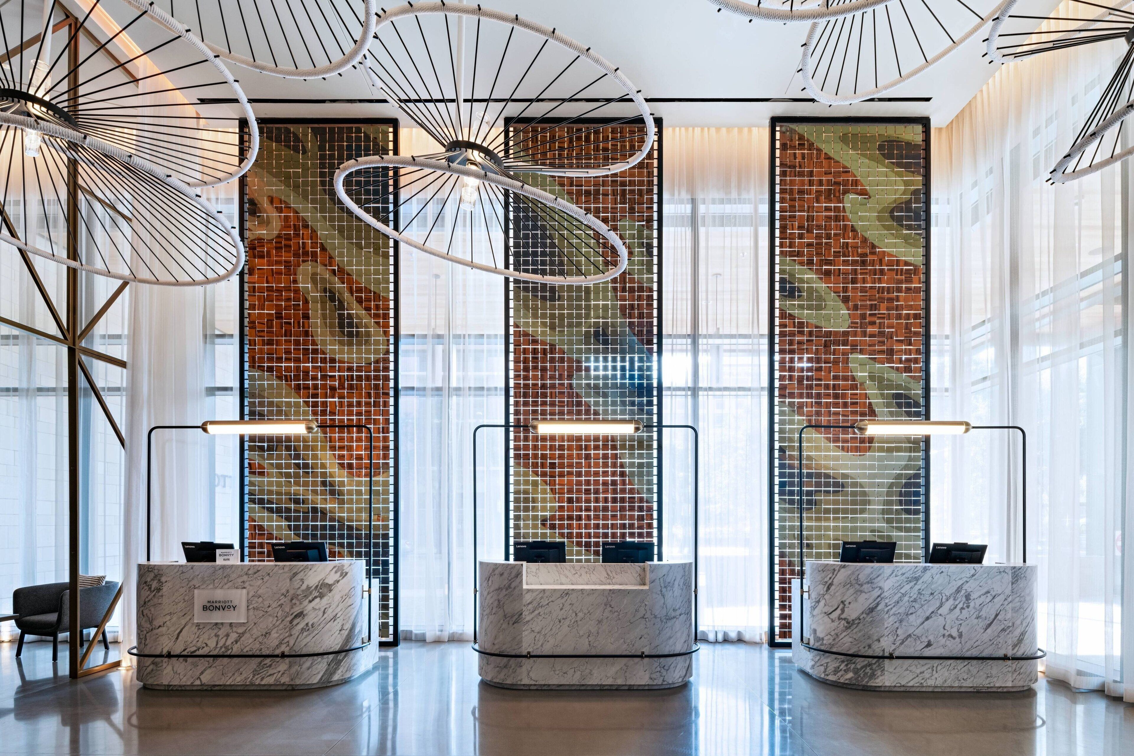 A reception area with marble counters, a modern chandelier, and a mosaic wall.