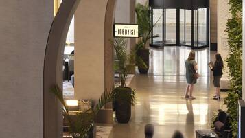 Um saguão com teto curvo, plantas em vasos e uma placa com a inscrição 'The Lobbyist'.